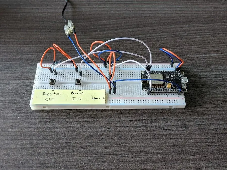 Breadboard with a tiny microcontroller, jumper wires, and buttons for 'Breathe out' and 'Breathe In'