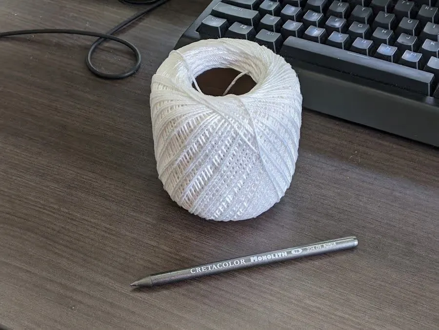 A ball of white string and a stick of graphite